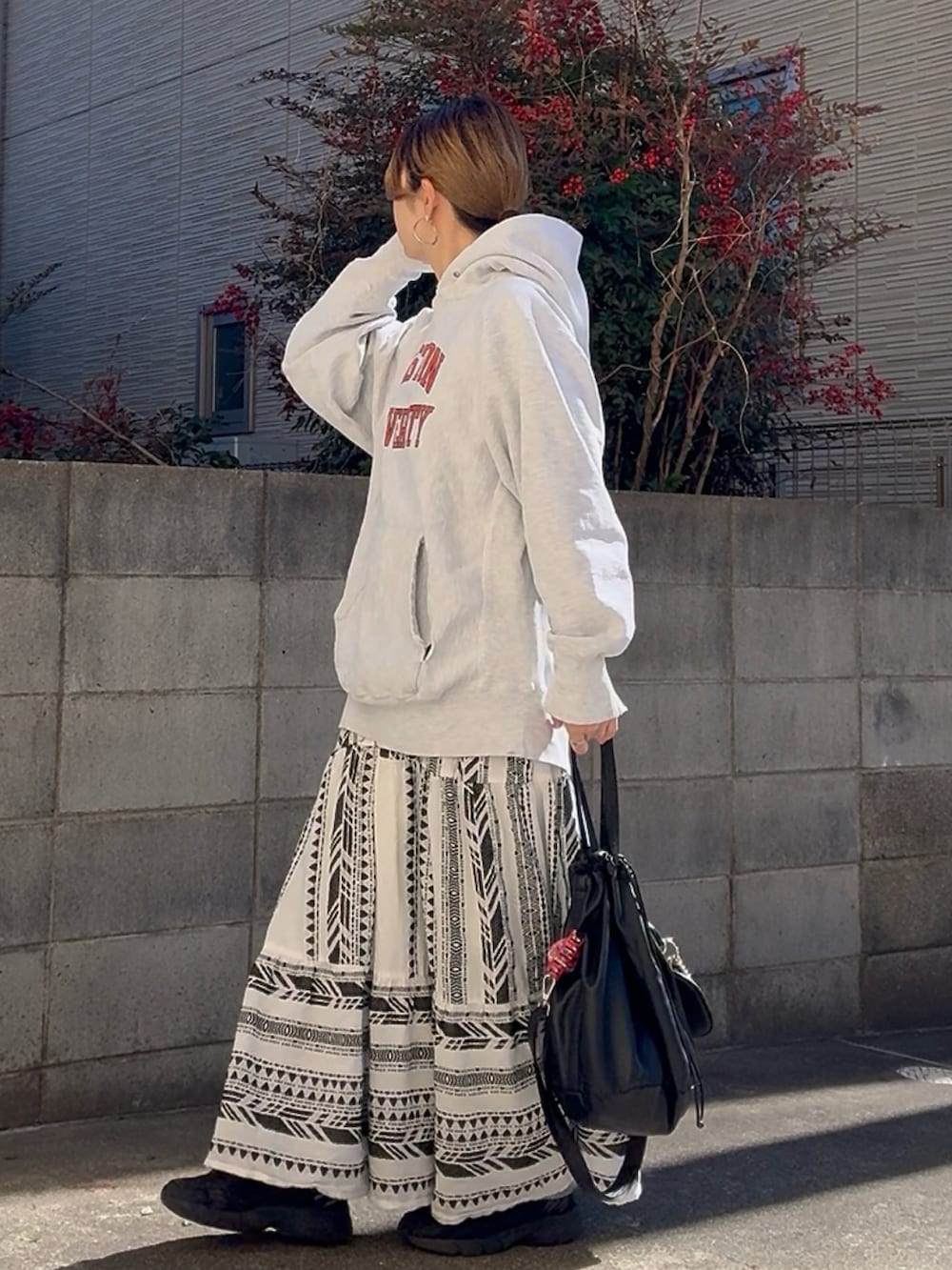 ブラック系のショルダーバッグ、ブラック系のスニーカー、グレー系のパーカーを着用したレディースの冬コーディネートの2枚目の写真