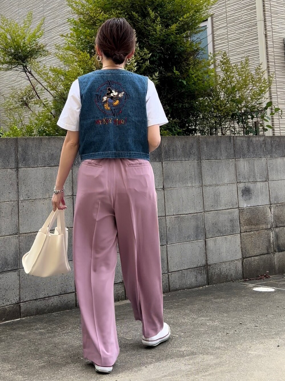 ブルー系のベスト、ベージュ系のTシャツ/カットソー、パープル系のスラックスを着用したレディースの春コーディネートの2枚目の写真