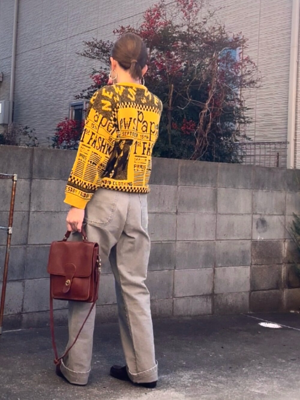 イエロー系のニット/セーター、グレー系のパンツ、ブラウン系のショルダーバッグを着用したレディースの冬コーディネートの3枚目の写真