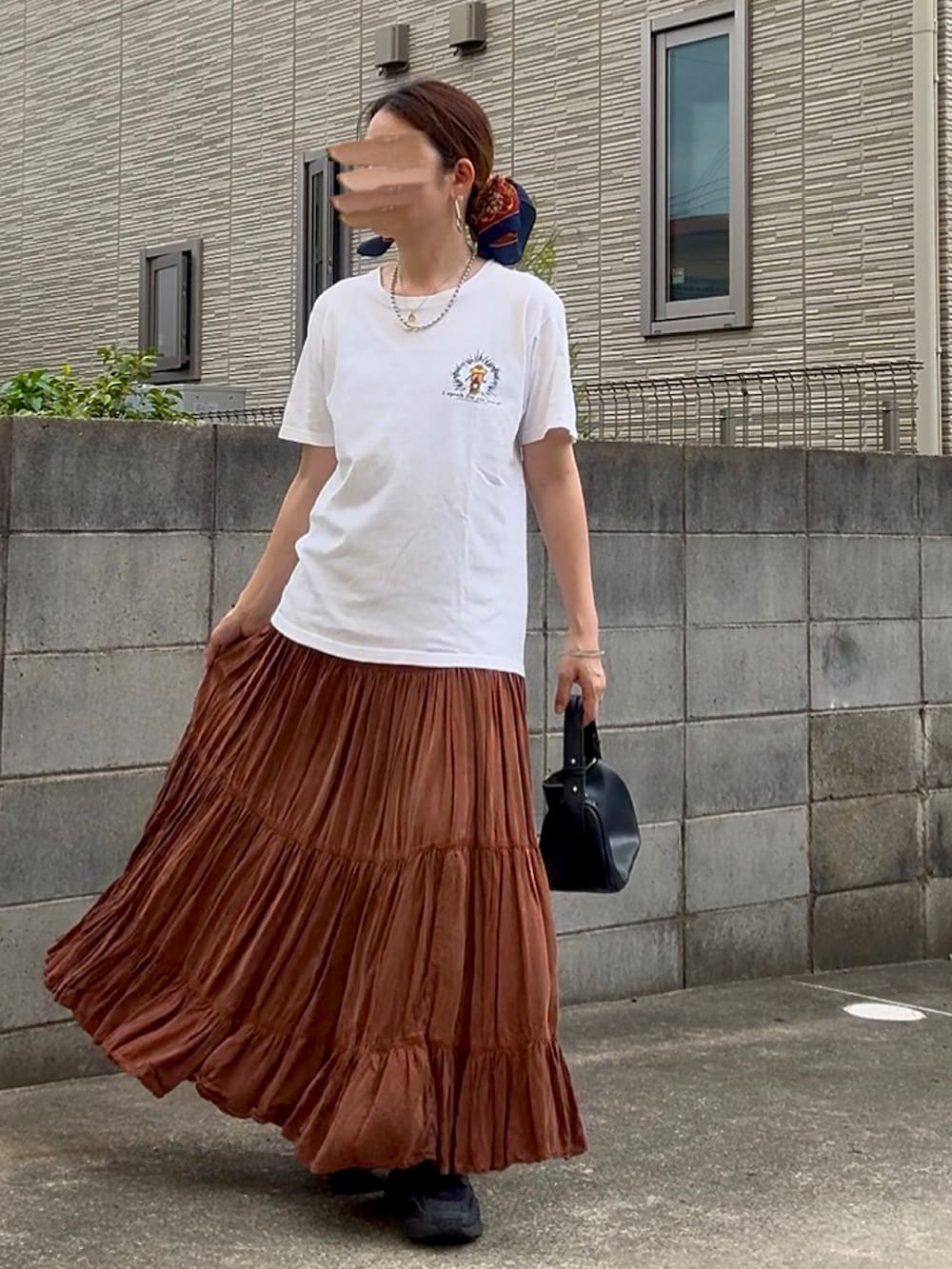 ブラック系のハンドバッグ、ブラック系のスニーカー、ホワイト系のTシャツ/カットソーを着用したレディースの春コーディネートの2枚目の写真