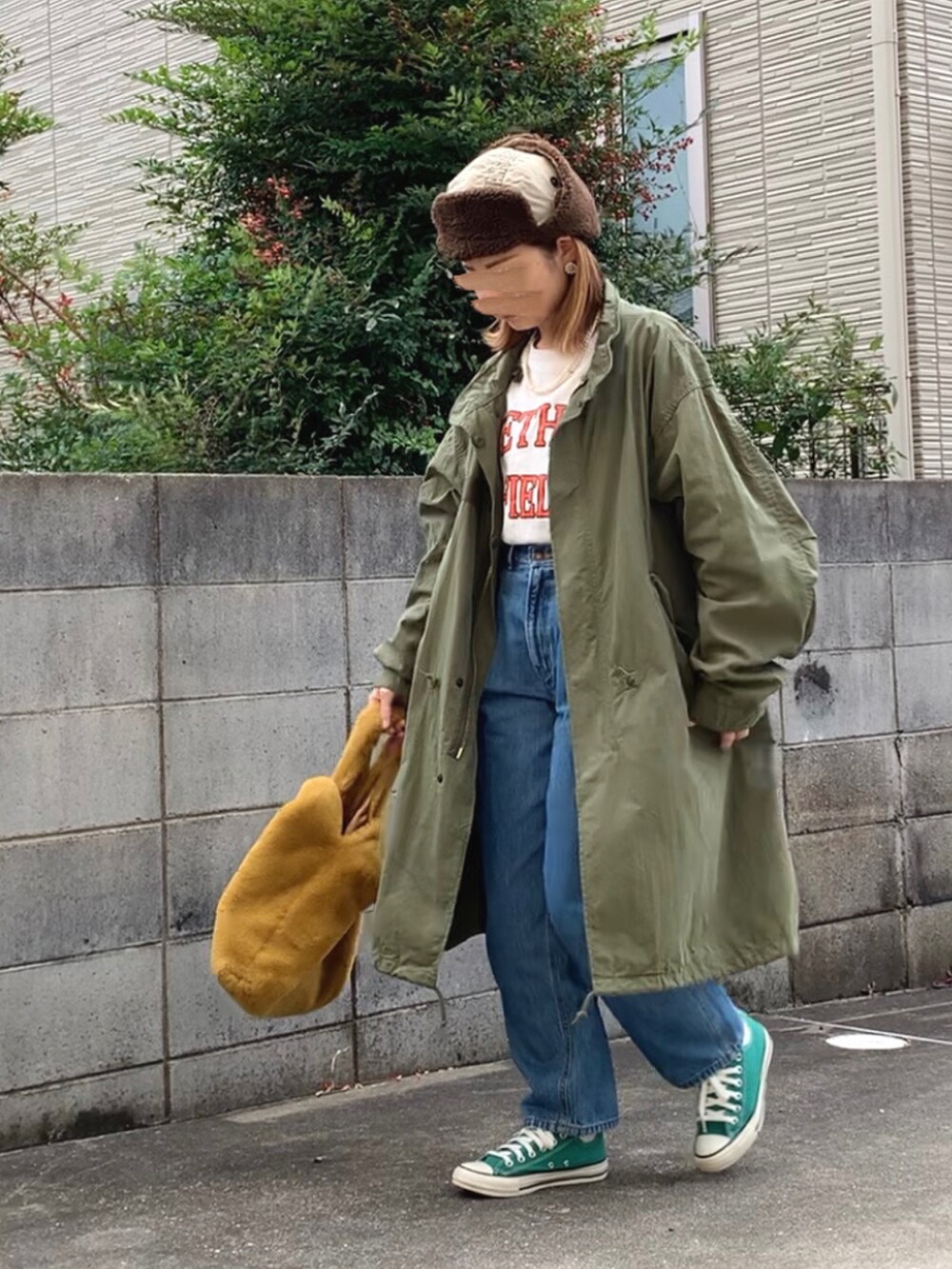 グリーン系のモッズコート、ホワイト系のTシャツ/カットソー、ブルー系のデニムパンツを着用したレディースの秋コーディネートの2枚目の写真