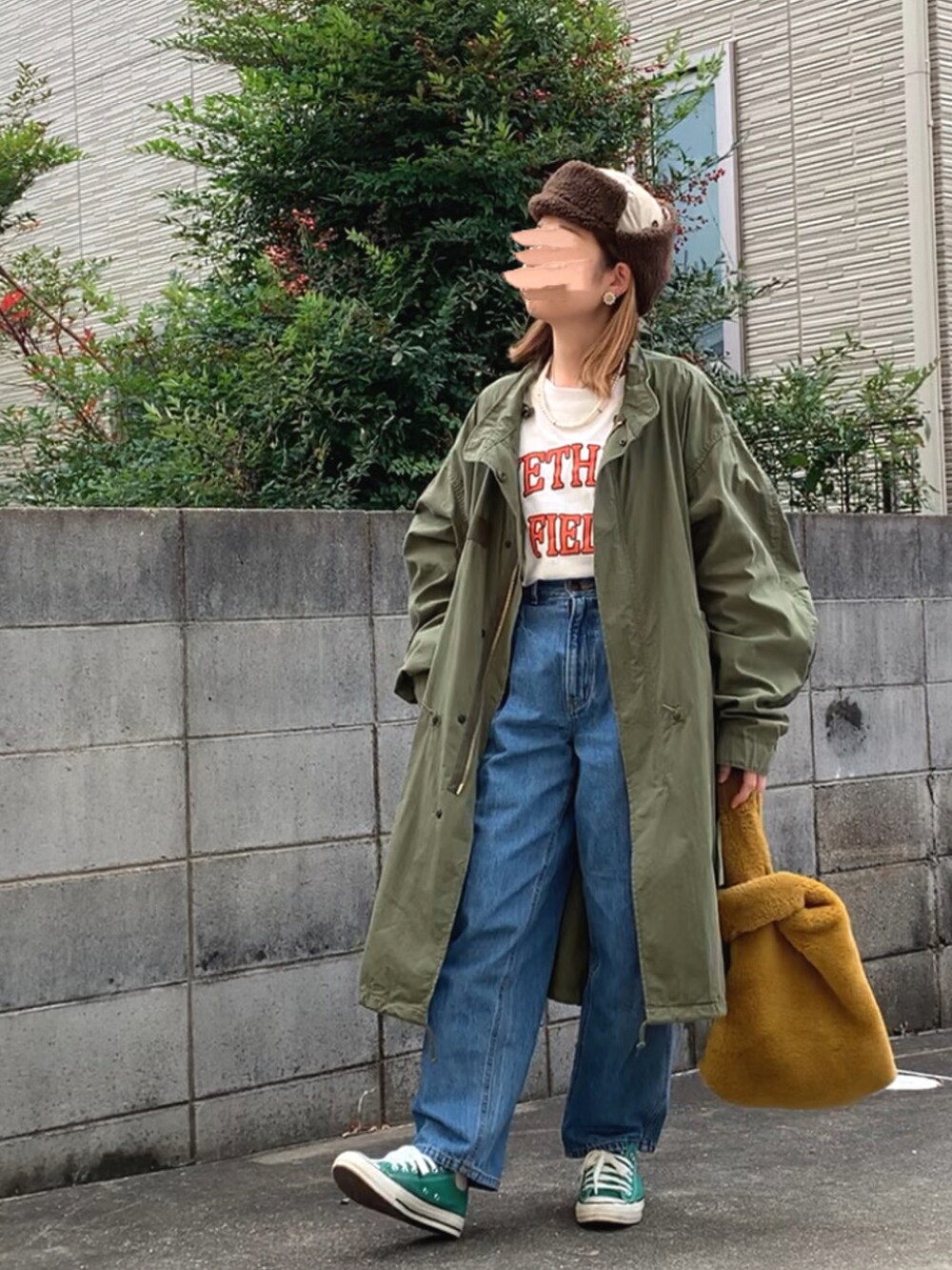 グリーン系のモッズコート、ホワイト系のTシャツ/カットソー、ブルー系のデニムパンツを着用したレディースの秋コーディネートの3枚目の写真