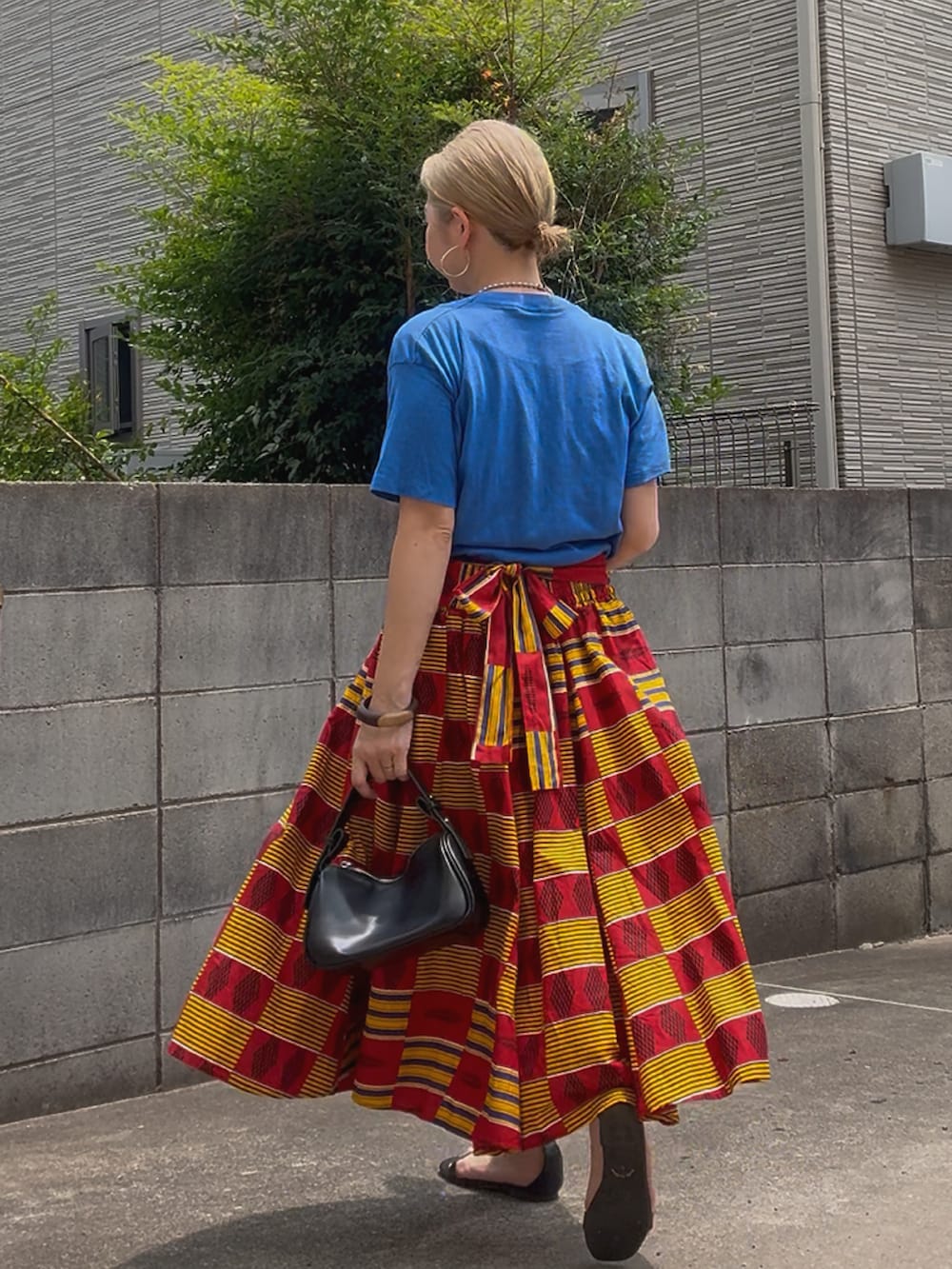 ブルー系のTシャツ/カットソー、レッド系のスカート、ブラック系のハンドバッグを着用したレディースの夏コーディネートの3枚目の写真