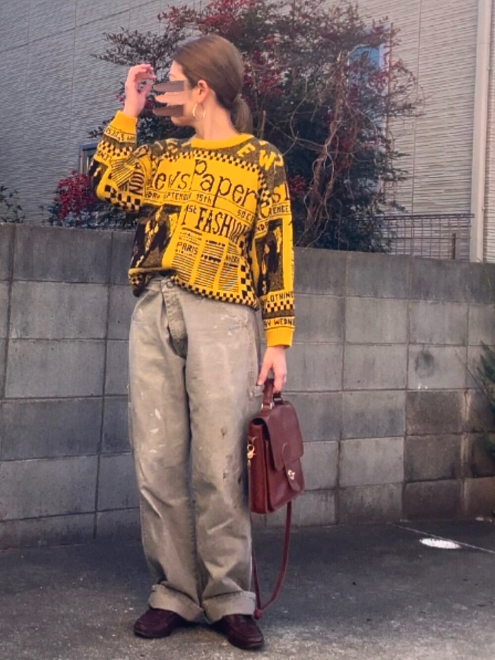 イエロー系のニット/セーター、グレー系のパンツ、ブラウン系のショルダーバッグを着用したレディースの冬コーディネートの2枚目の写真