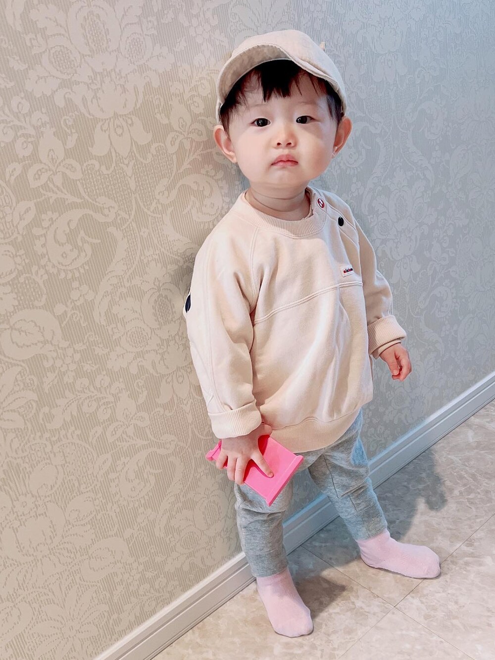 グレー系のスウェットパンツ、ベージュ系のスウェット、ベージュ系のキャップを着用したキッズの春コーディネートの2枚目の写真