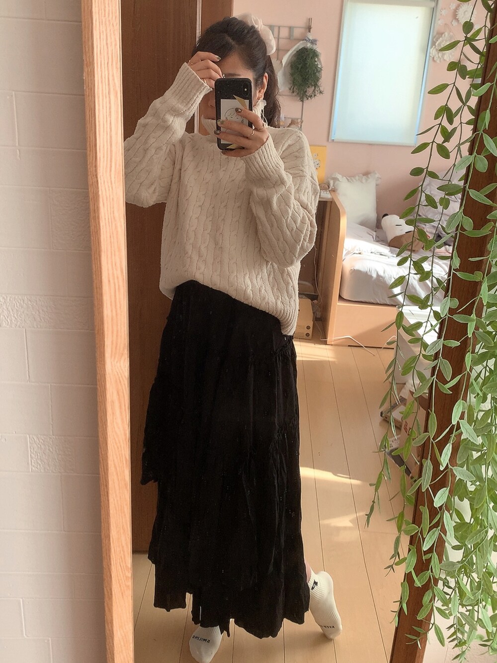 ブラウン系のステンカラーコート、ブラック系のスカート、ホワイト系のニット/セーターを着用したレディースの冬コーディネートの2枚目の写真