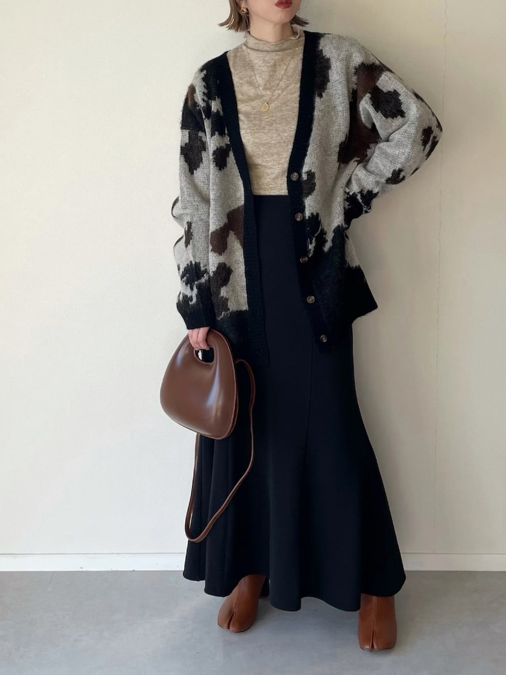 ブラック系のカーディガン/ボレロ、ブラック系のスカート、ブラウン系のブーツを着用したレディースの冬コーディネートの2枚目の写真