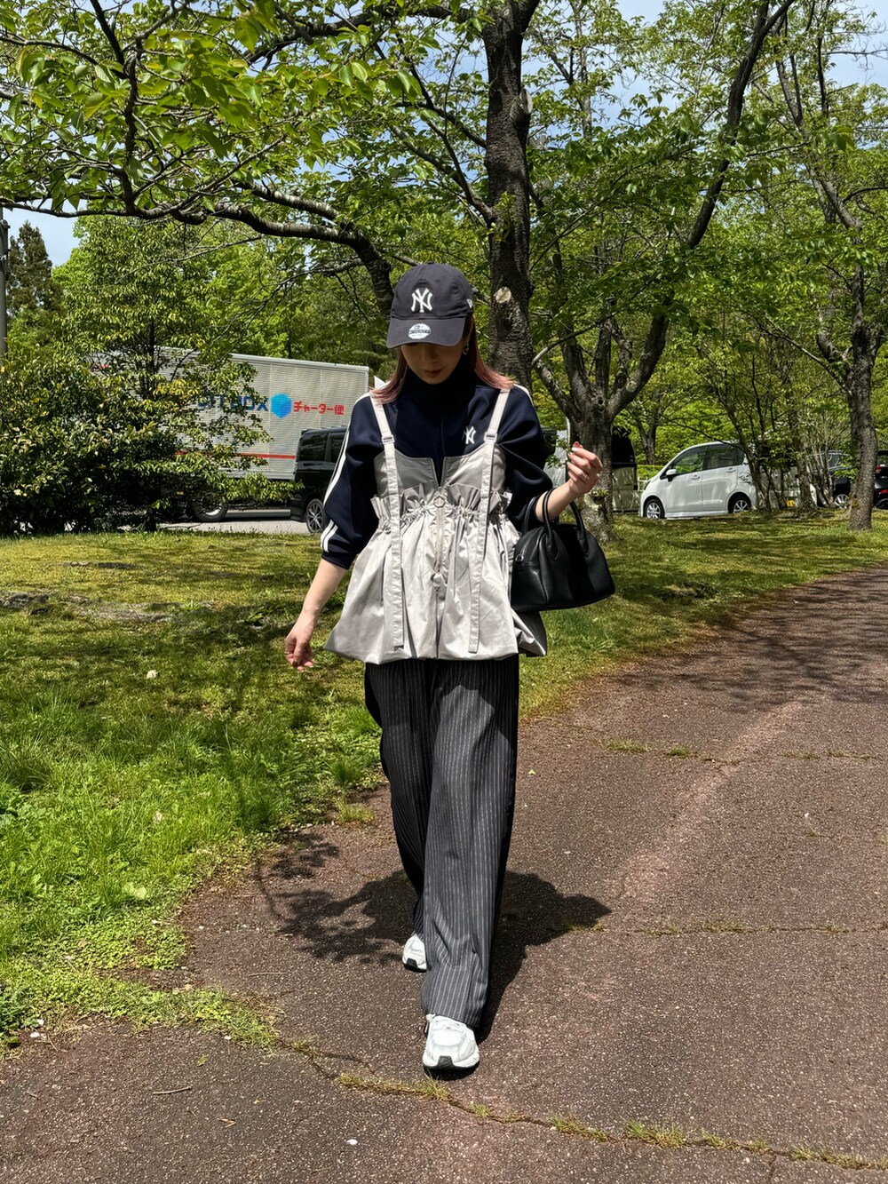 グレー系のスラックス、グレー系のスニーカー、ブラック系のショルダーバッグを着用したレディースの春コーディネートの2枚目の写真