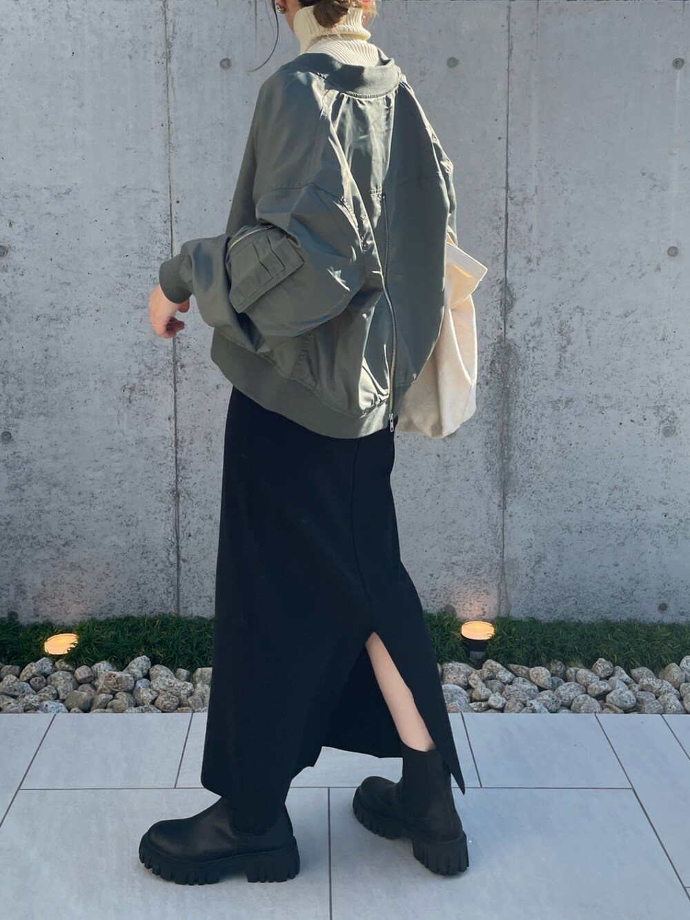 グリーン系のブルゾン、ホワイト系のニット/セーター、ブラック系のブーツを着用したレディースの秋コーディネートの4枚目の写真