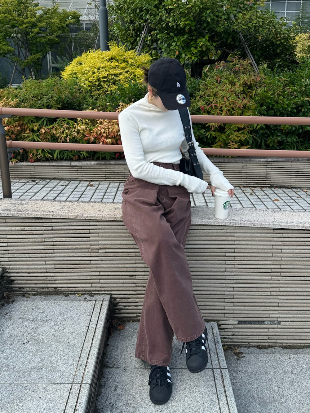 ホワイト系のニット/セーター、ブラウン系のデニムパンツ、ブラック系のスニーカーを着用したレディースの秋コーディネートの2枚目の写真