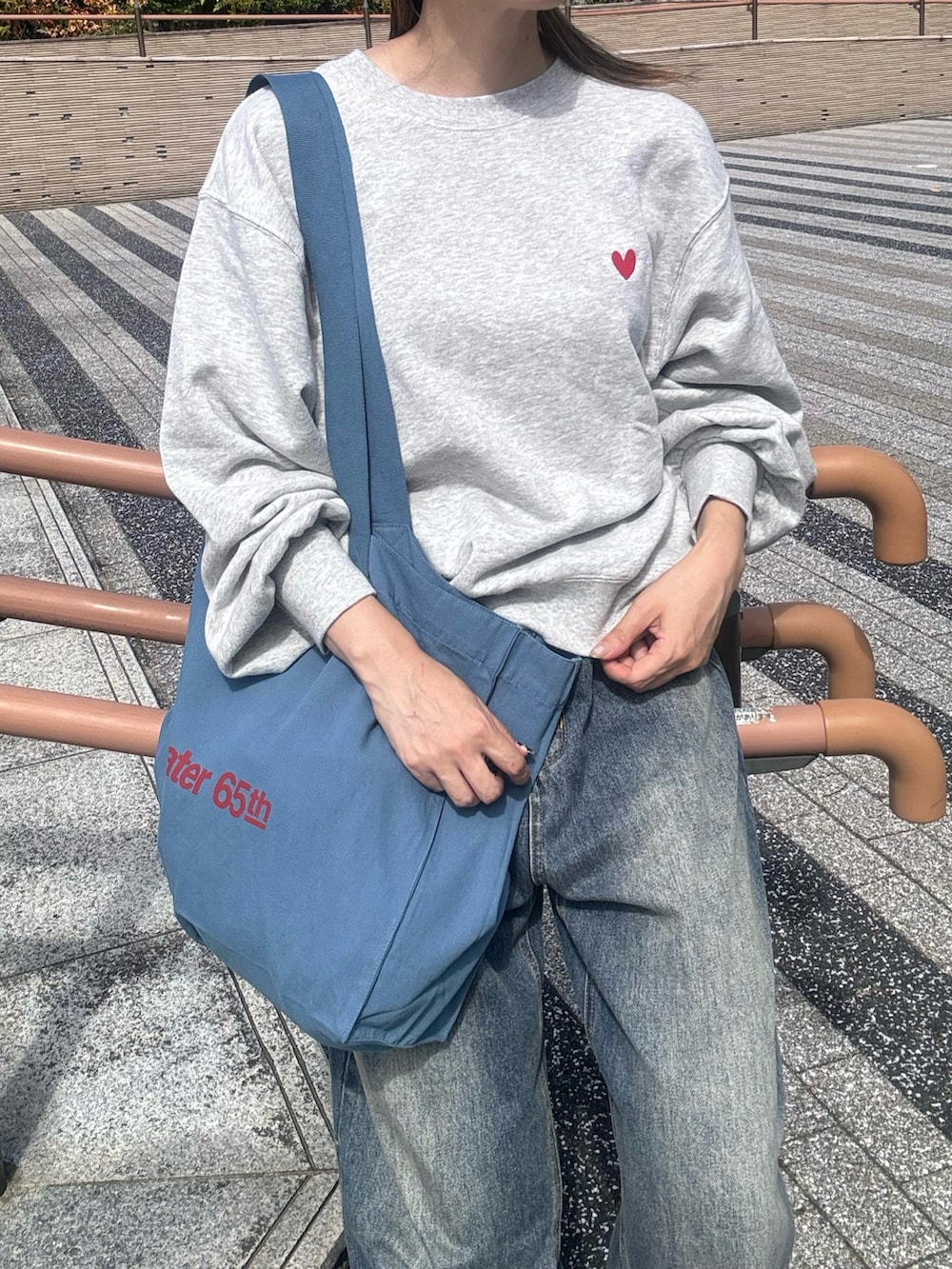 グレー系のスウェット、ブルー系のトートバッグ、ブルー系のデニムパンツを着用したレディースの秋コーディネートの5枚目の写真