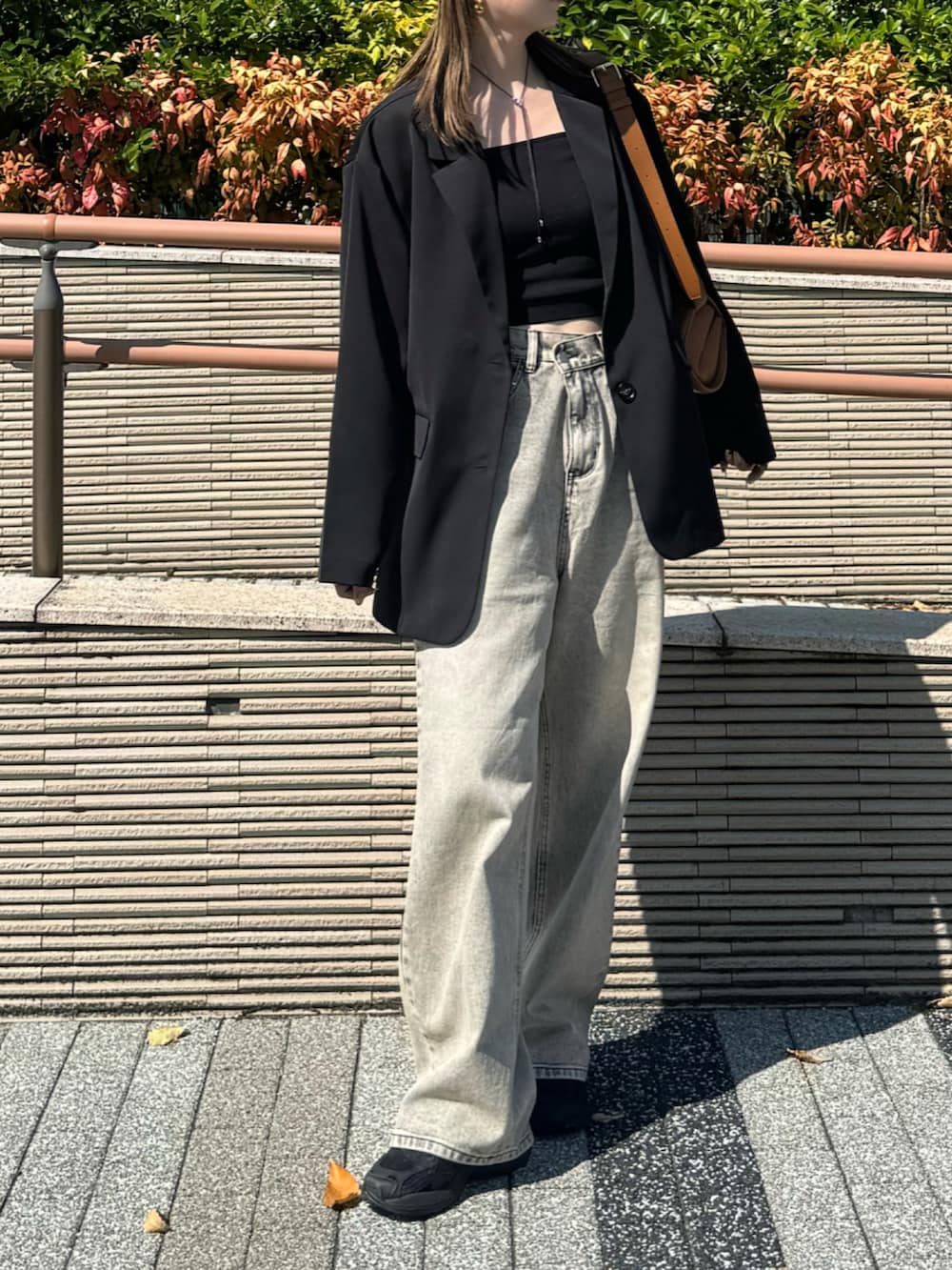 ブラック系のテーラードジャケット、ベージュ系のデニムパンツ、ベージュ系のショルダーバッグを着用したレディースの秋コーディネートの3枚目の写真