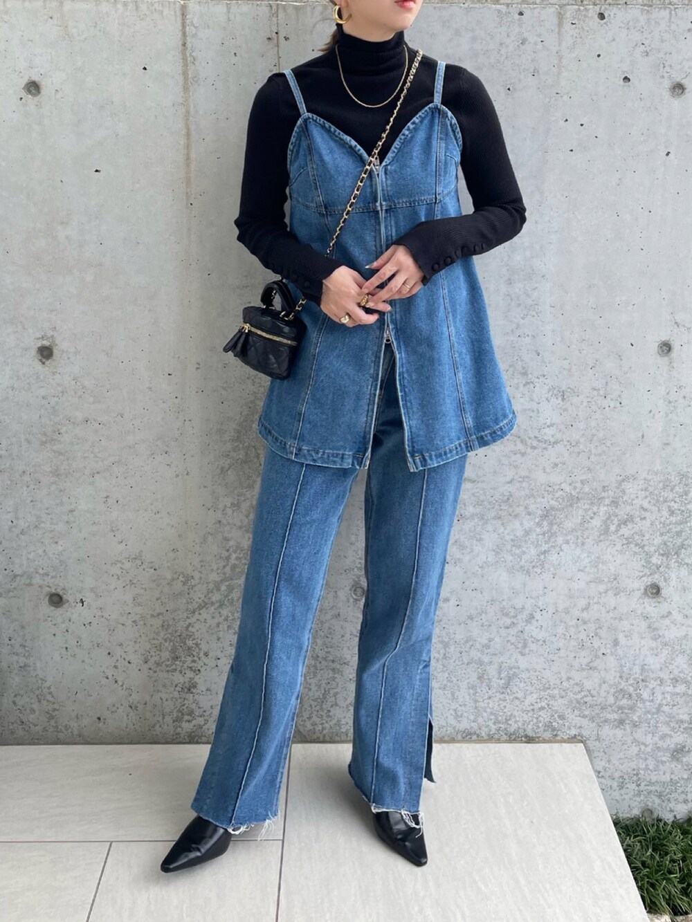 ブラック系のパンプス、ブルー系のデニムパンツ、ブルー系のベストを着用したレディースの秋コーディネートの3枚目の写真