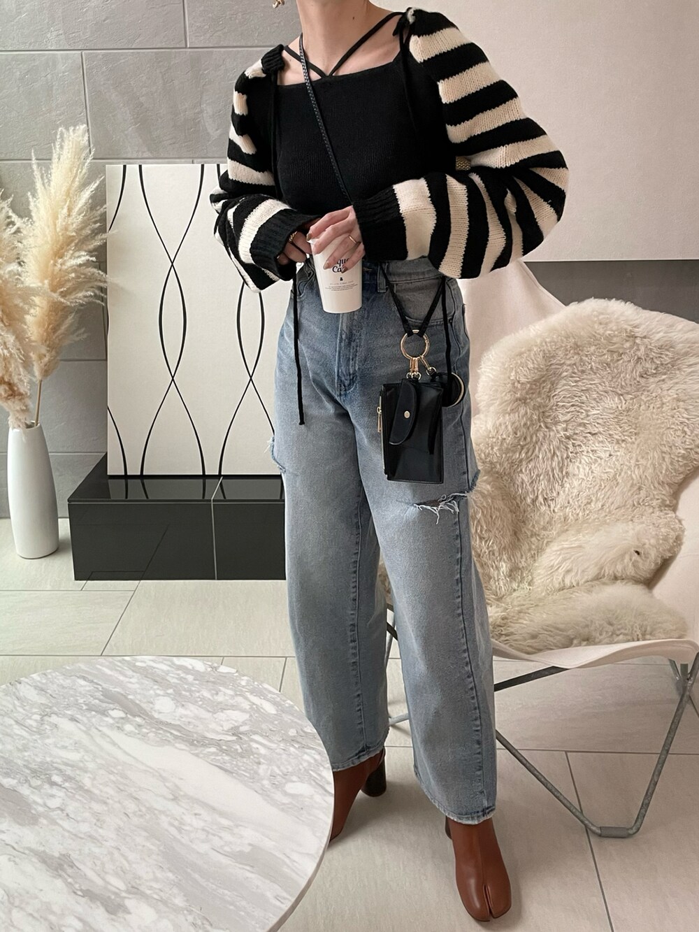 ブラック系のニット/セーター、ブラウン系のブーツ、ブラック系のショルダーバッグを着用したレディースの冬コーディネートの5枚目の写真