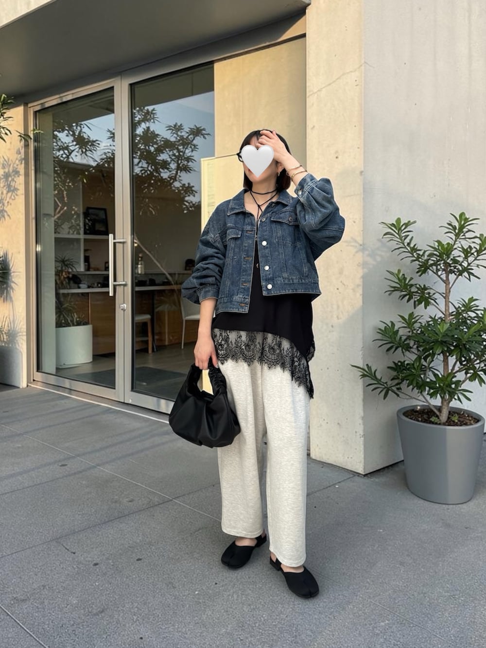 グレー系のデニムパンツ、ブラック系のショルダーバッグ、ブラック系のサンダルを着用したレディースの春コーディネートの3枚目の写真