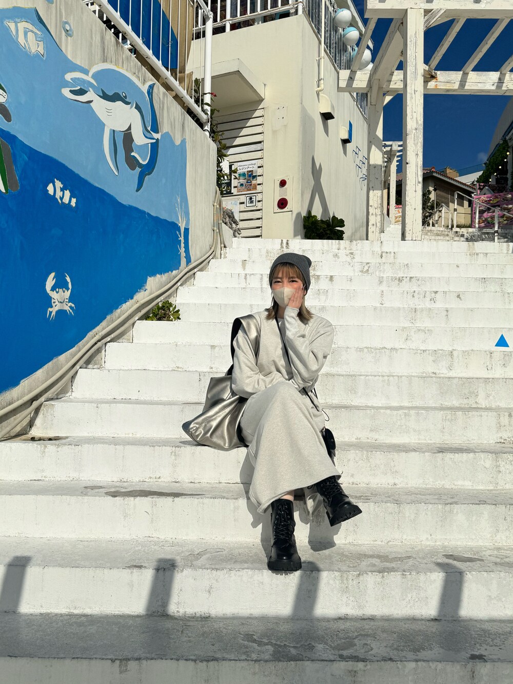 シルバー系のトートバッグ、ブラック系のブーツ、グレー系のニットキャップ/ビーニーを着用したレディースの冬コーディネートの2枚目の写真