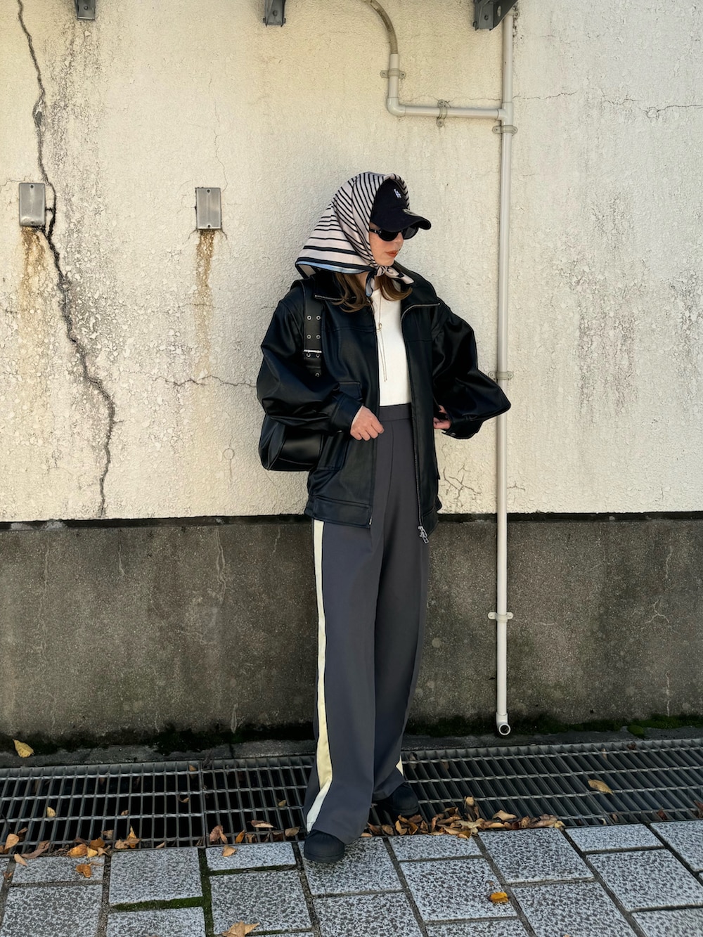 グレー系のスラックス、ブラック系のライダースジャケット、ブラック系のハンドバッグを着用したレディースの秋コーディネートの2枚目の写真
