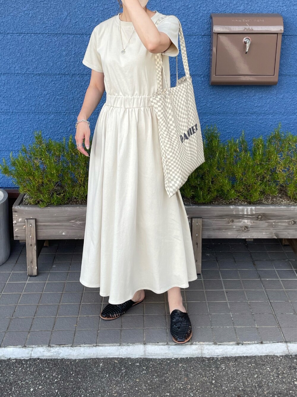 ベージュ系のワンピース、ベージュ系のトートバッグ、ブラック系のサンダルを着用したレディースの夏コーディネートの2枚目の写真