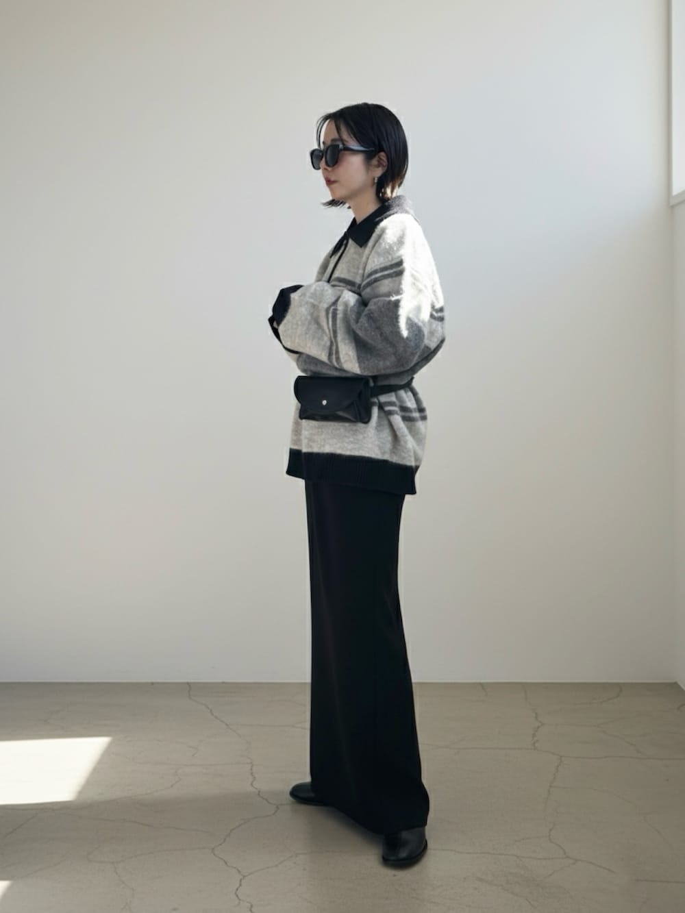 グレー系のニット/セーター、ブラック系のスカート、ブラック系のボディバッグ/ウエストポーチを着用したレディースの冬コーディネートの2枚目の写真