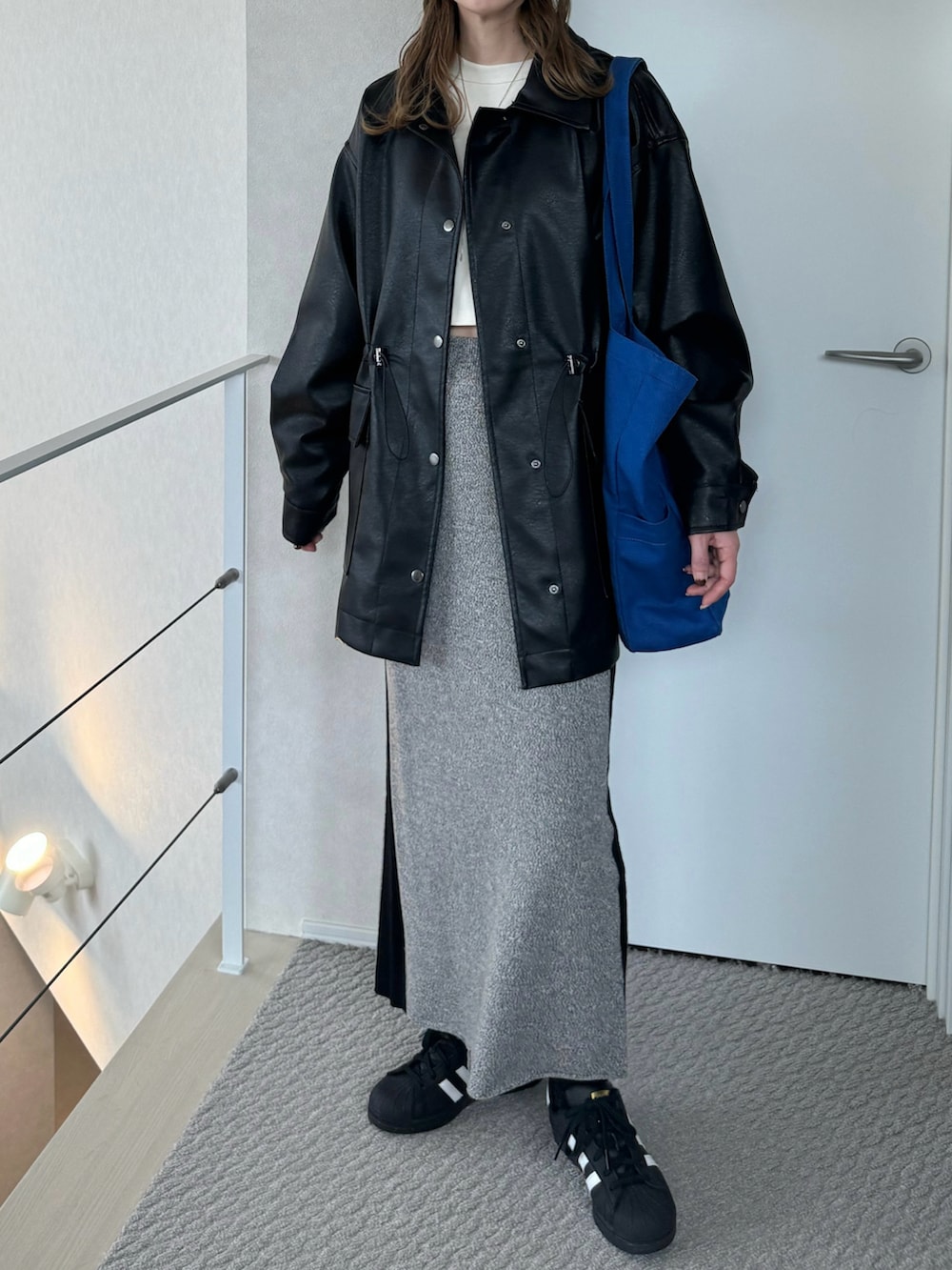 ブラック系のその他アウター、ホワイト系のTシャツ/カットソー、グレー系のスカートを着用したレディースの冬コーディネートの2枚目の写真