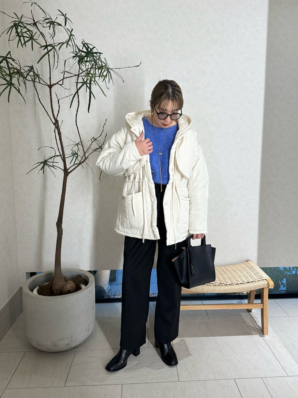 ブラック系のスラックス、ブルー系のニット/セーター、ブラック系のハンドバッグを着用したレディースの秋コーディネートの3枚目の写真