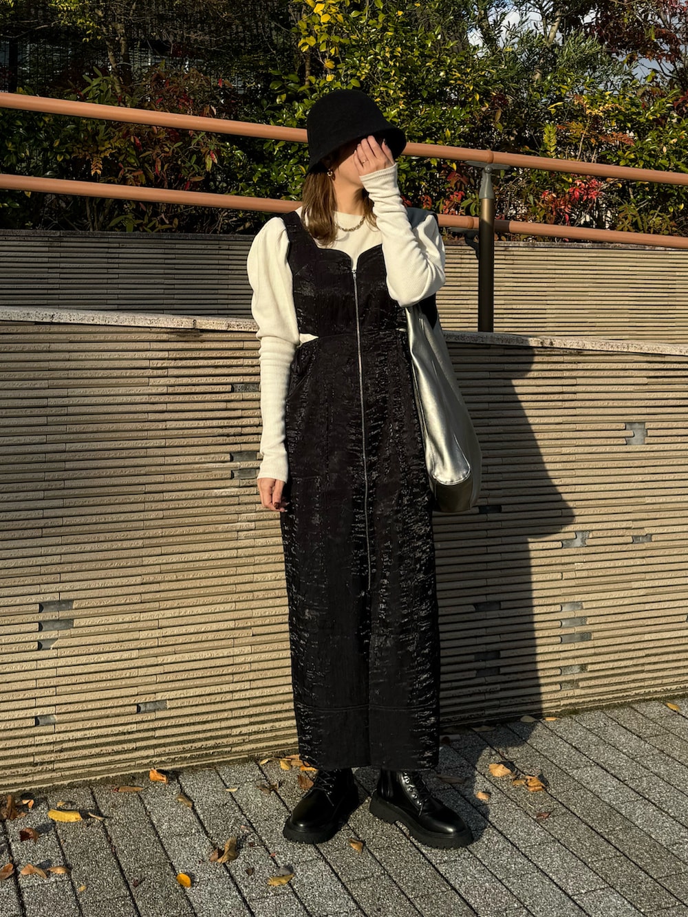 ブラック系のジャンパースカート、ホワイト系のTシャツ/カットソー、ブラック系のブーツを着用したレディースの秋コーディネートの3枚目の写真