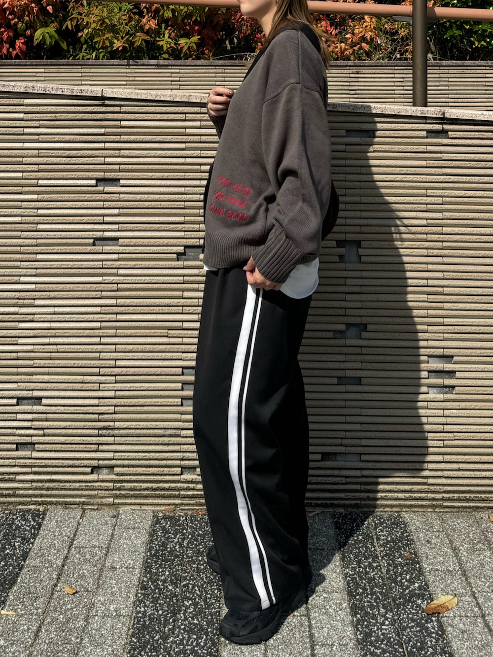 グレー系のニット/セーター、ブラック系のショルダーバッグ、ブラック系のスラックスを着用したレディースの秋コーディネートの4枚目の写真