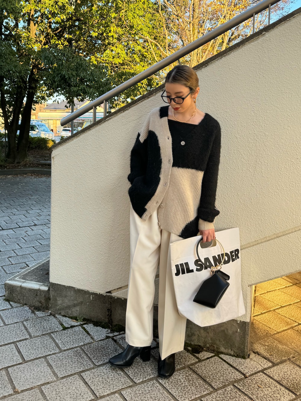 ブラック系のカーディガン/ボレロ、ホワイト系のその他パンツ、ブラック系のハンドバッグを着用したレディースの秋コーディネートの2枚目の写真