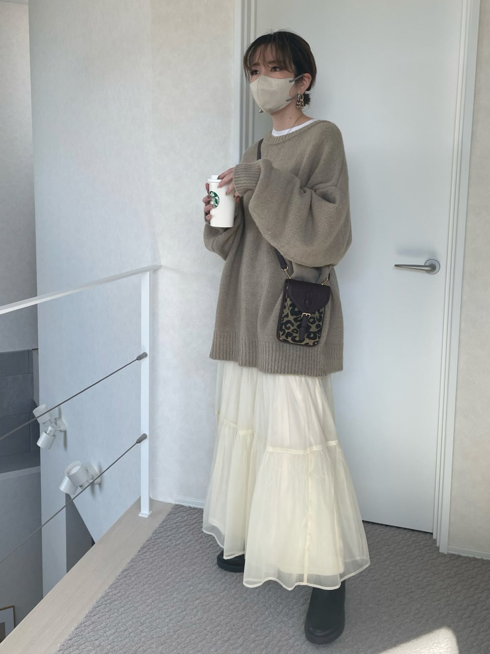 ベージュ系のカーディガン/ボレロ、ホワイト系のスカート、ブラウン系のショルダーバッグを着用したレディースの冬コーディネートの4枚目の写真