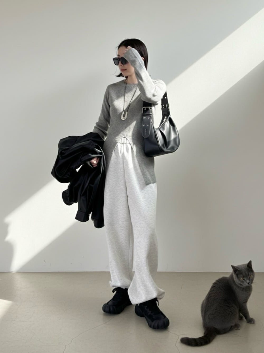 グレー系のニット/セーター、グレー系のスウェットパンツ、ブラック系のスニーカーを着用したレディースの冬コーディネートの2枚目の写真