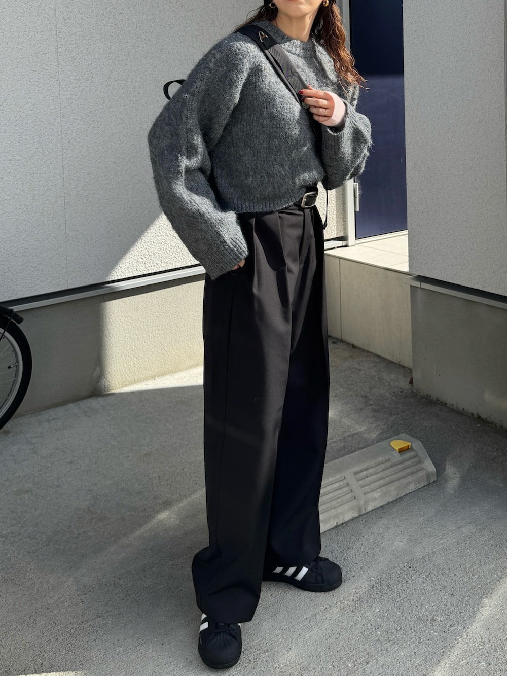 グレー系のニット/セーター、ブラック系のその他パンツ、ブラック系のボディバッグ/ウエストポーチを着用したレディースの秋コーディネートの2枚目の写真