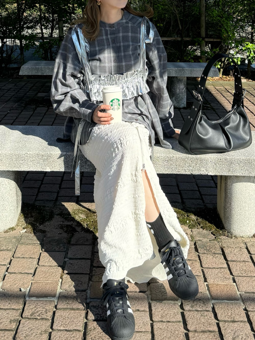 ホワイト系のスカート、ブラック系のスニーカー、ブラック系のハンドバッグを着用したレディースの秋コーディネートの3枚目の写真