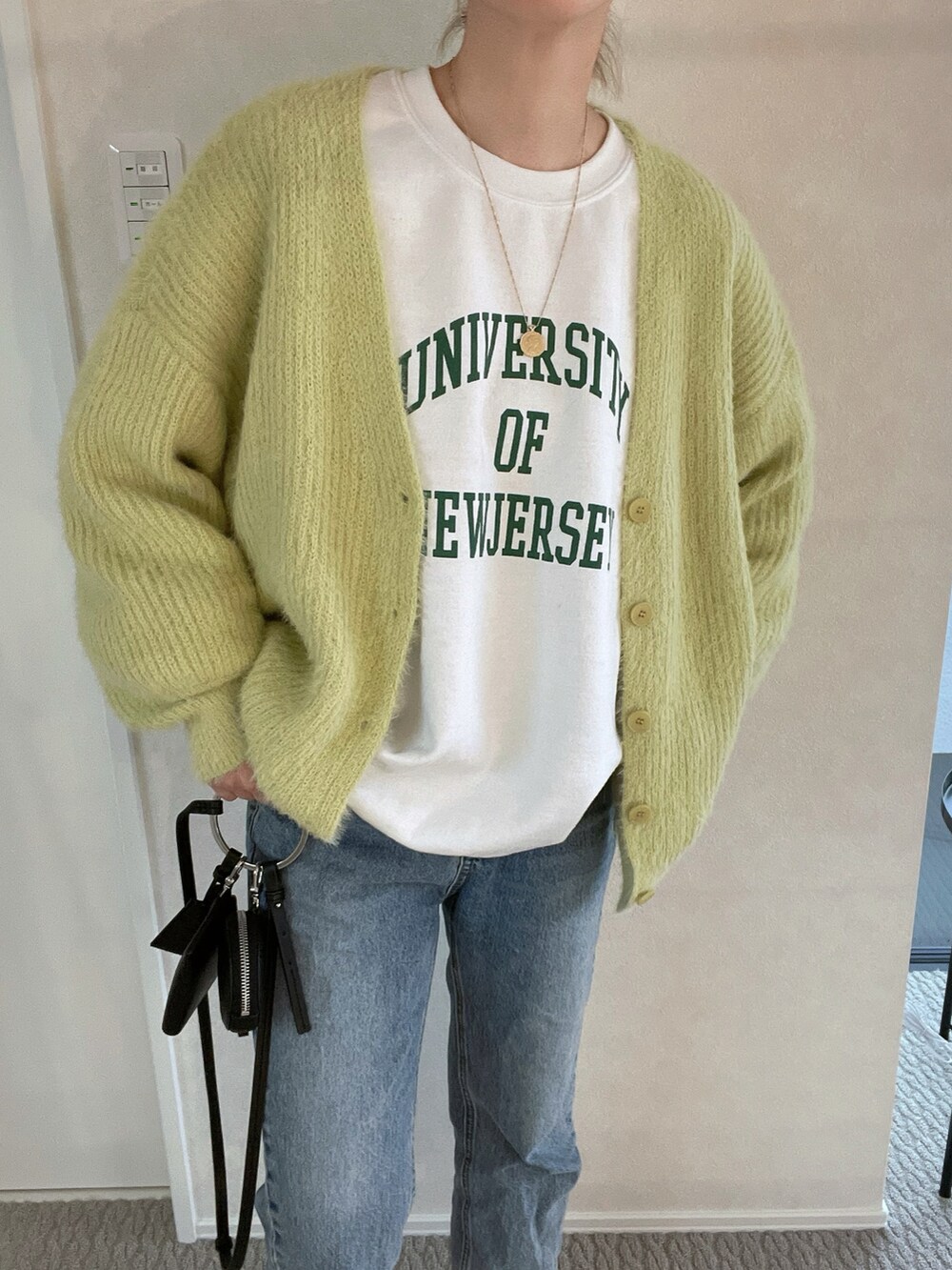 グリーン系のカーディガン/ボレロ、ホワイト系のスウェット、ブルー系のデニムパンツを着用したレディースの秋コーディネートの2枚目の写真