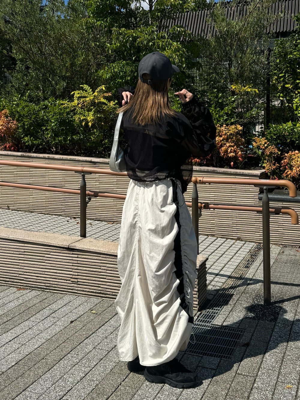 ホワイト系のスカート、ブラック系のブルゾン、シルバー系のショルダーバッグを着用したレディースの秋コーディネートの3枚目の写真