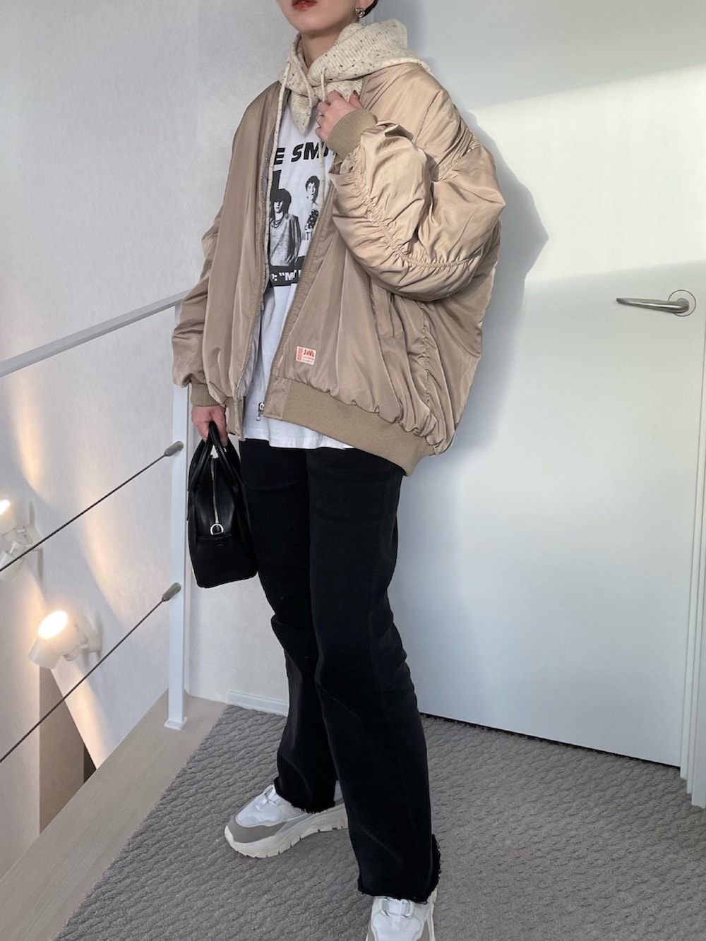 ベージュ系のMA-1、ホワイト系のスニーカー、ブラック系のボストンバッグを着用したレディースの冬コーディネートの2枚目の写真