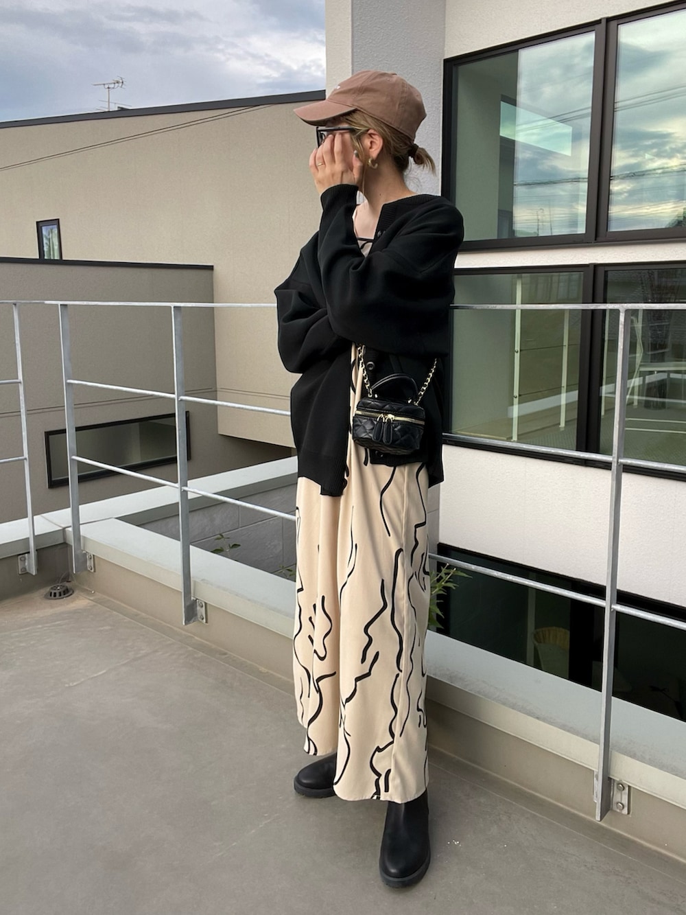 ブラック系のカーディガン/ボレロ、ホワイト系のワンピース、ブラック系のブーツを着用したレディースの秋コーディネートの2枚目の写真