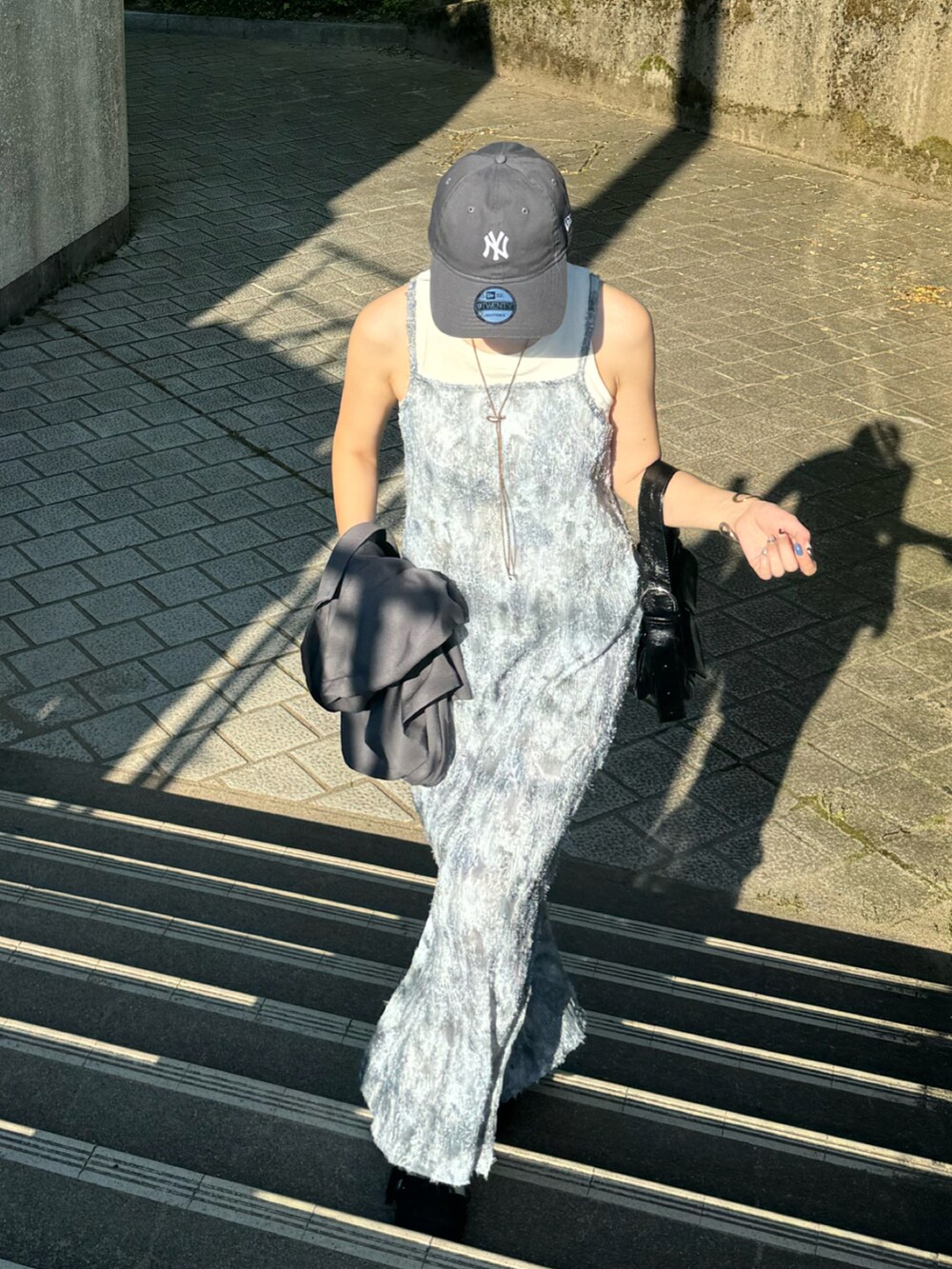 グレー系のワンピース、ブラック系のスニーカー、ブラック系のショルダーバッグを着用したレディースの夏コーディネートの4枚目の写真