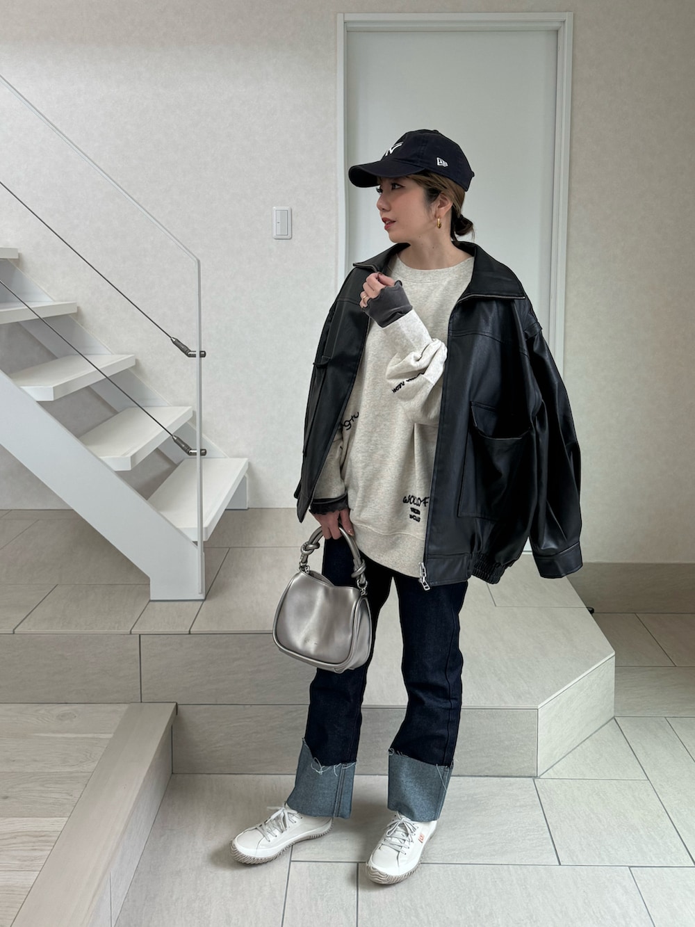 ホワイト系のスウェット、シルバー系のショルダーバッグ、ブラック系のライダースジャケットを着用したレディースの冬コーディネートの2枚目の写真