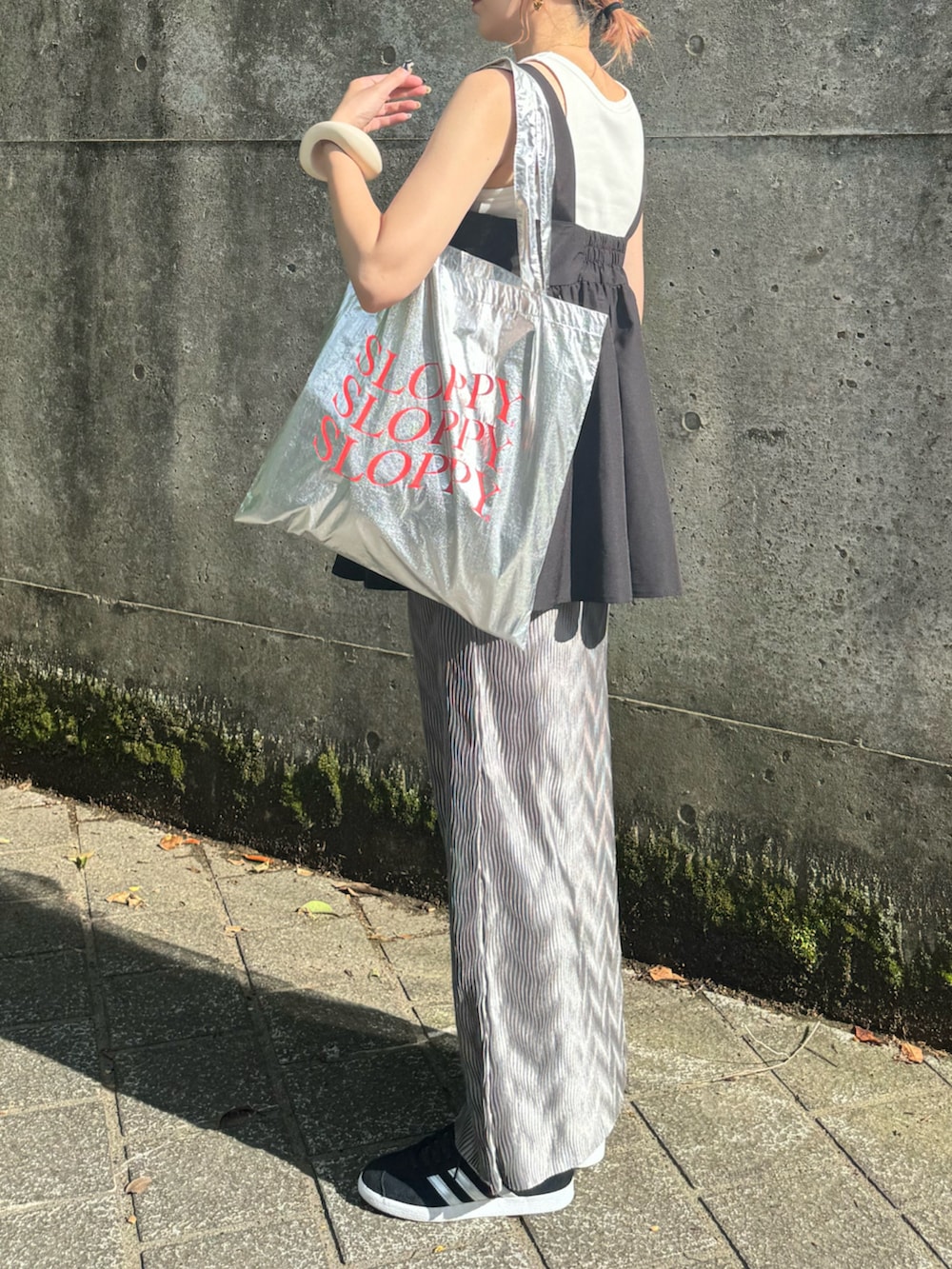 グレー系のスカート、ブラック系のその他トップス、シルバー系のトートバッグを着用したレディースの夏コーディネートの3枚目の写真