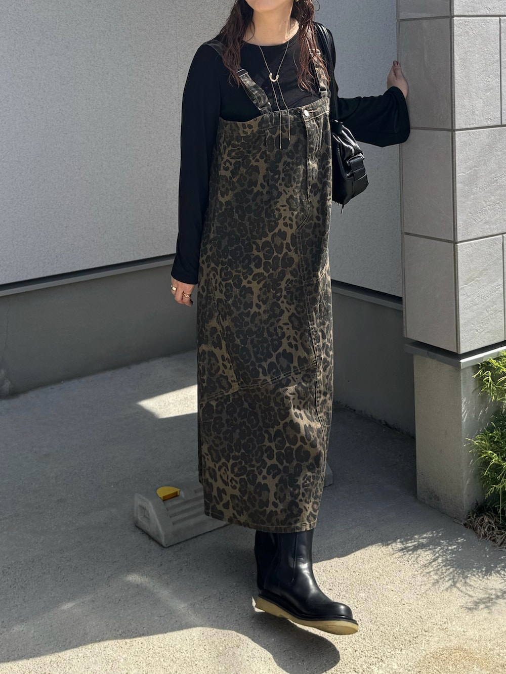 ブラック系のボストンバッグ、ブラック系のブーツ、ブラウン系のキャップを着用したレディースの秋コーディネートの3枚目の写真