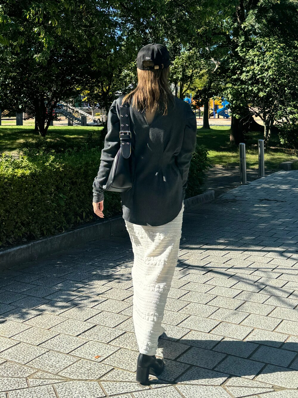 ホワイト系のスカート、グレー系のTシャツ/カットソー、ブラック系のハンドバッグを着用したレディースの秋コーディネートの2枚目の写真