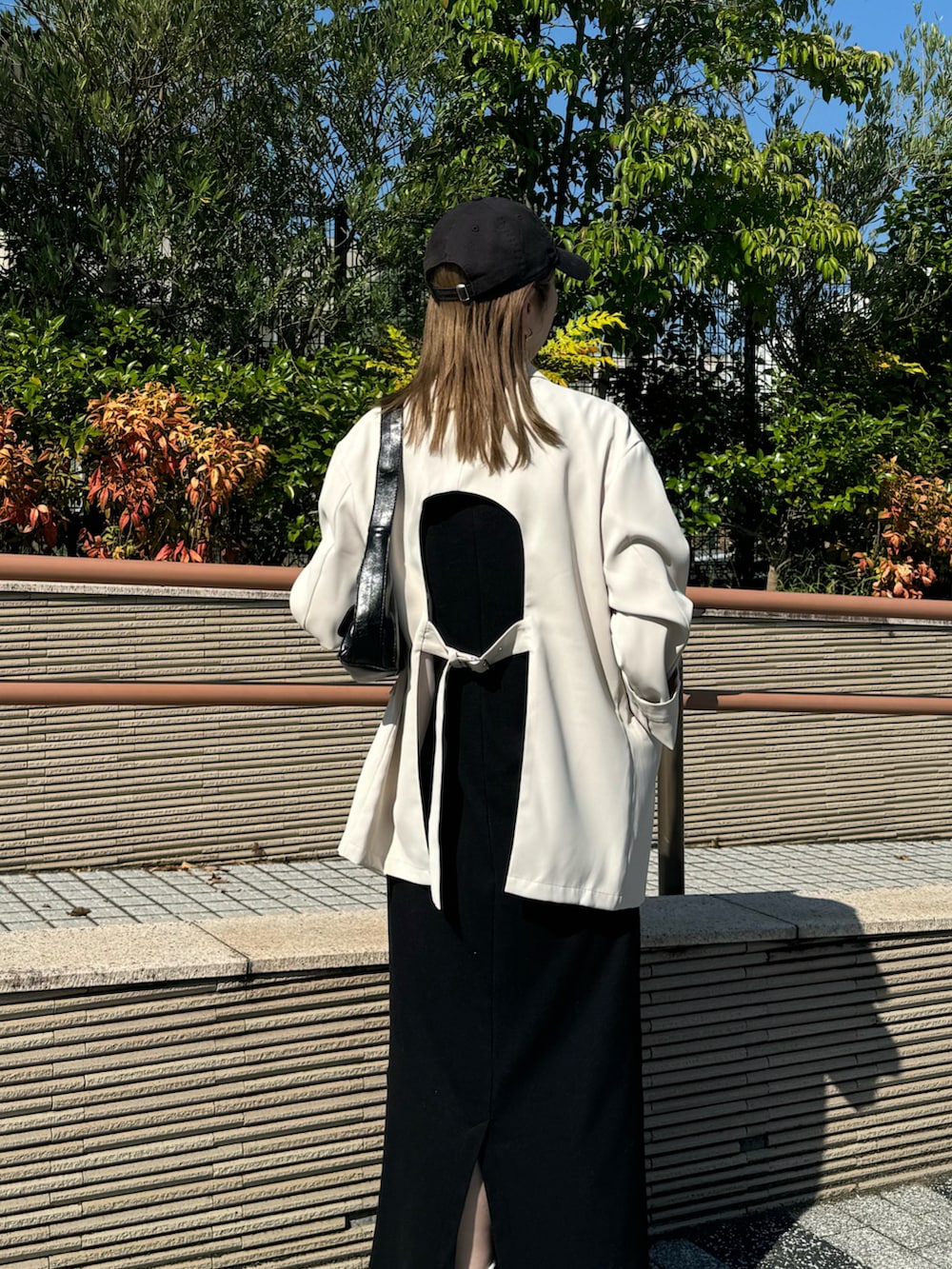 ホワイト系のテーラードジャケット、レッド系のスニーカー、ブラック系のワンピースを着用したレディースの秋コーディネートの4枚目の写真