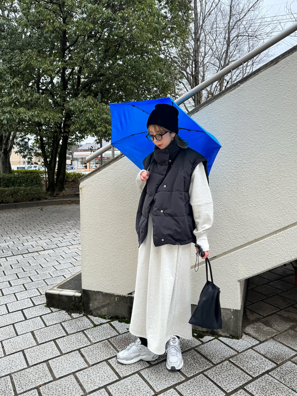 グレー系のスニーカー、ブルー系の折りたたみ傘を着用したレディースの冬コーディネートの2枚目の写真