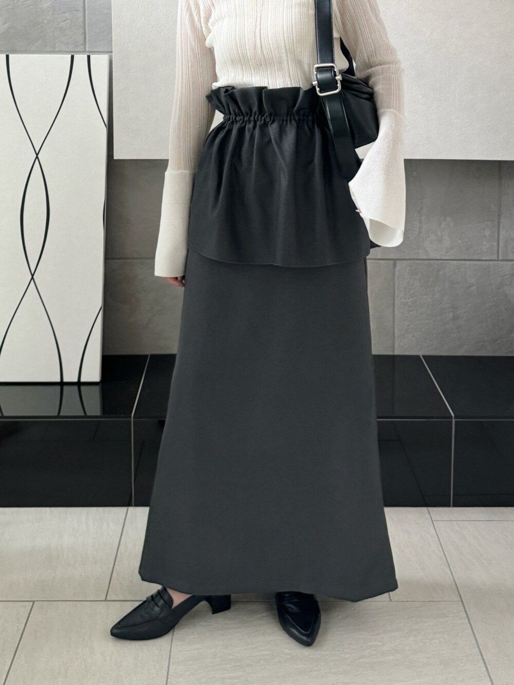 グレー系のスカート、ホワイト系のニット/セーター、ブラック系のローファーを着用したレディースの秋コーディネートの5枚目の写真