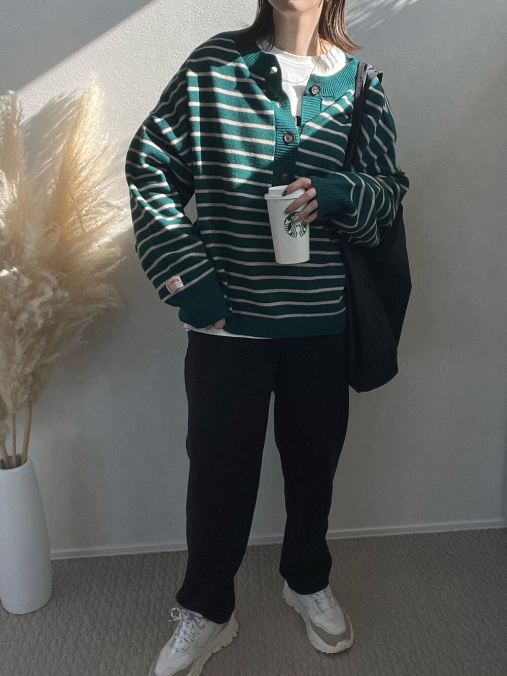 グリーン系のニット/セーター、ブラック系のショルダーバッグ、ホワイト系のスニーカーを着用したレディースの冬コーディネートの2枚目の写真