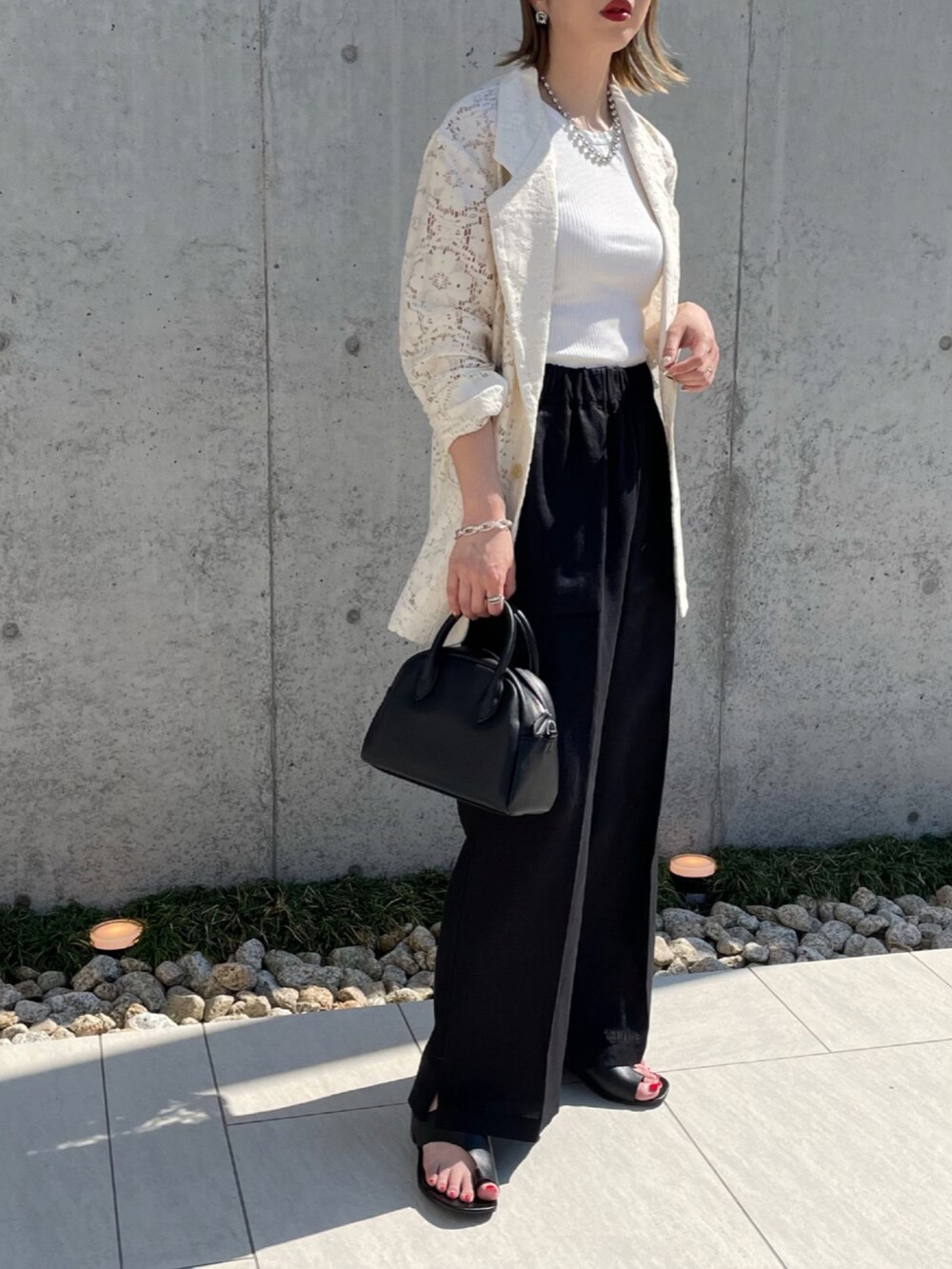 ブラック系のその他パンツ、ホワイト系のテーラードジャケット、ブラック系のサンダルを着用したレディースの春コーディネートの2枚目の写真