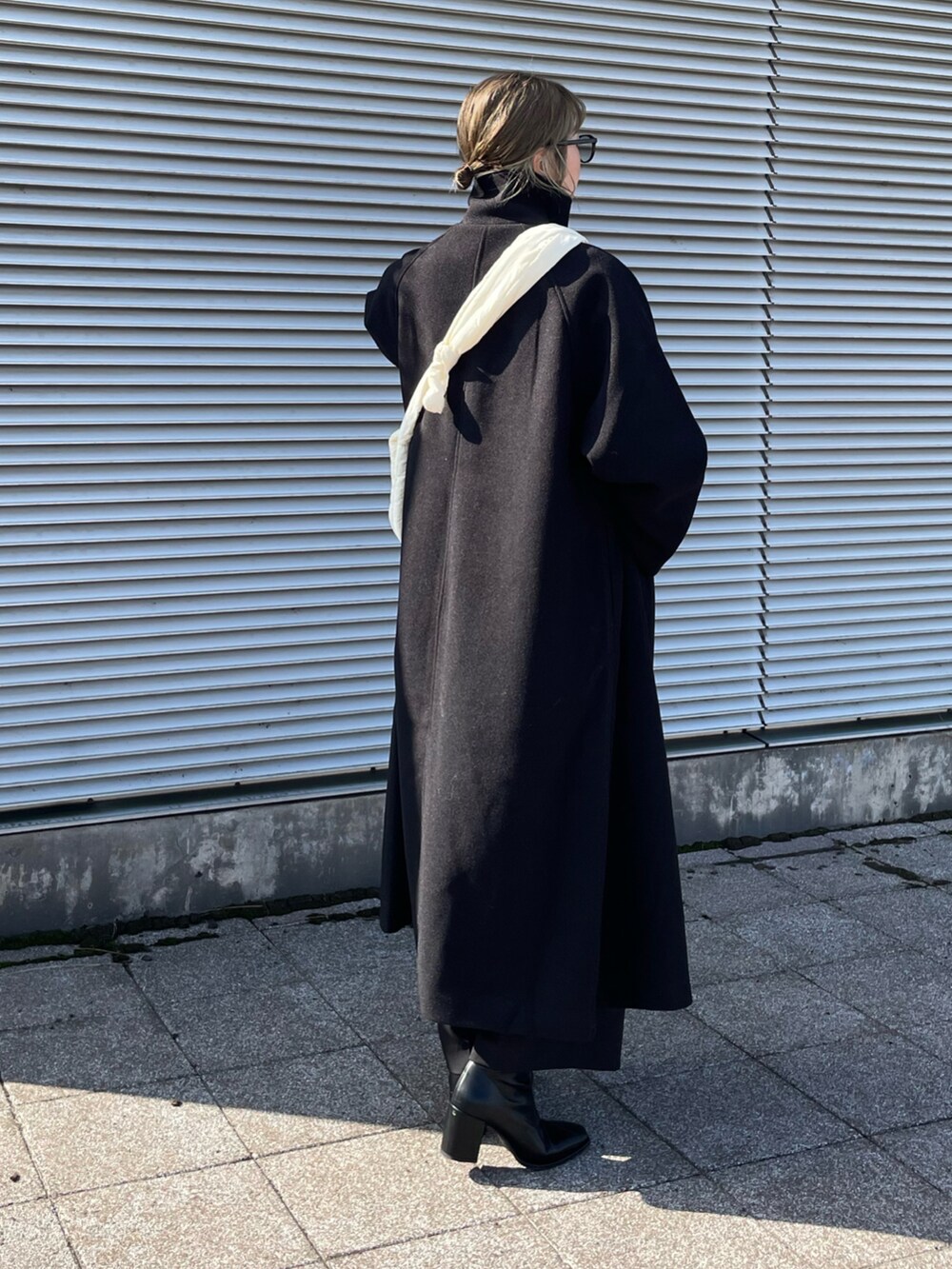 ブラック系のその他アウター、ホワイト系のニット/セーター、ブラック系のその他パンツを着用したレディースの秋コーディネートの4枚目の写真