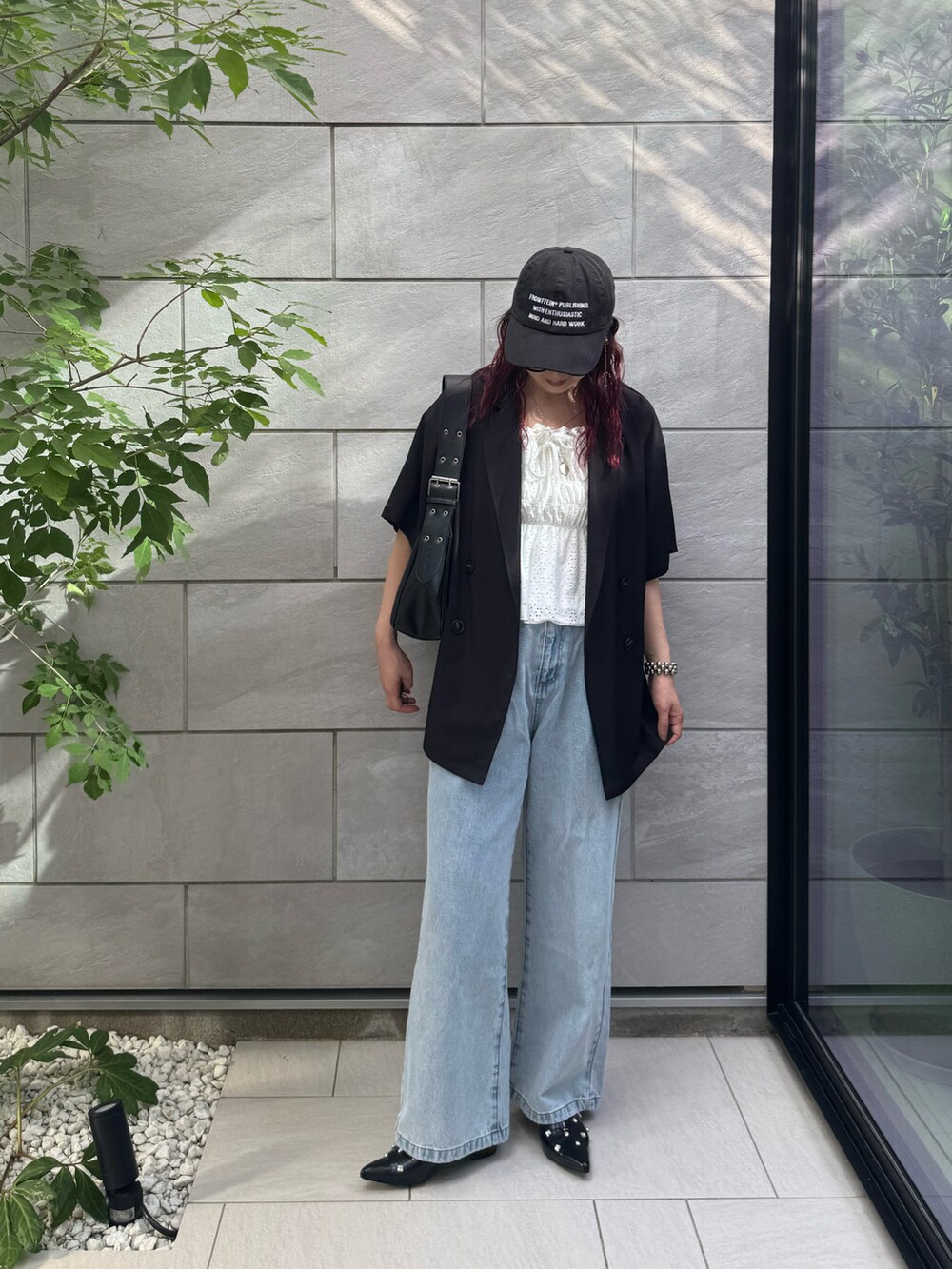 ブラック系のテーラードジャケット、ブラック系のパンプス、ブルー系のデニムパンツを着用したレディースの秋コーディネートの3枚目の写真
