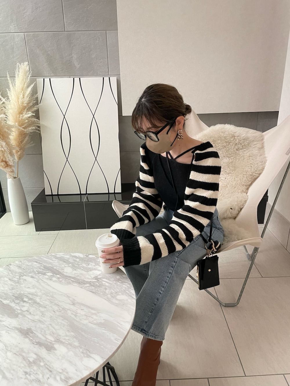 ブラック系のニット/セーター、ブラウン系のブーツ、ブラック系のショルダーバッグを着用したレディースの冬コーディネートの2枚目の写真