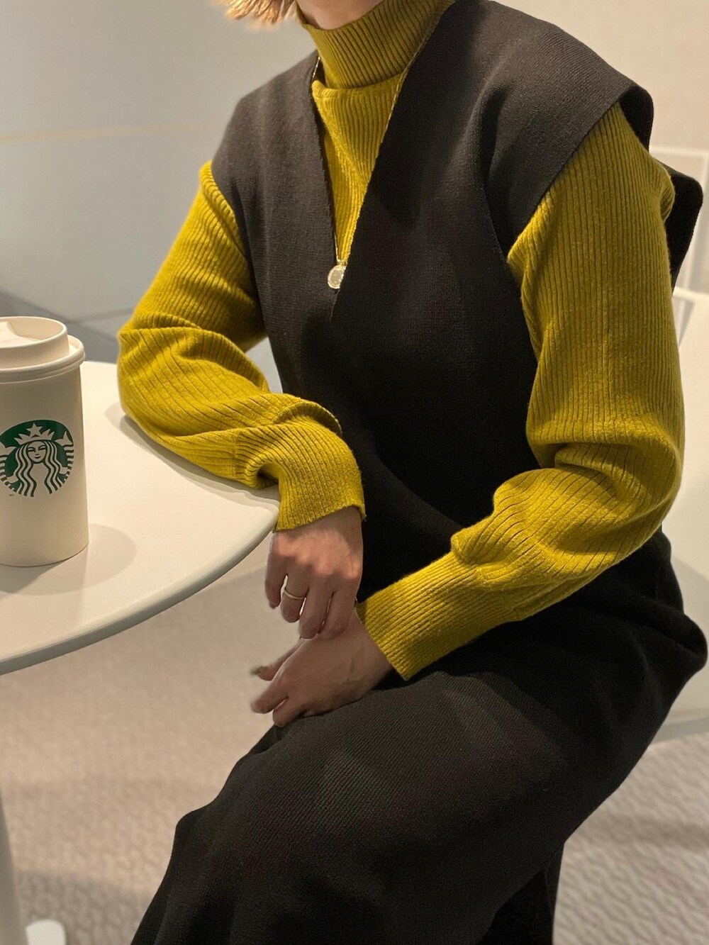 ブラック系のワンピース、グリーン系のニット/セーター、ゴールド系のネックレスを着用したレディースの冬コーディネートの3枚目の写真